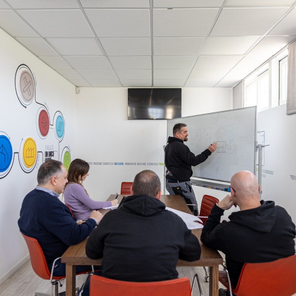 Team tecnico in riunione con schema progettuale su lavagna
